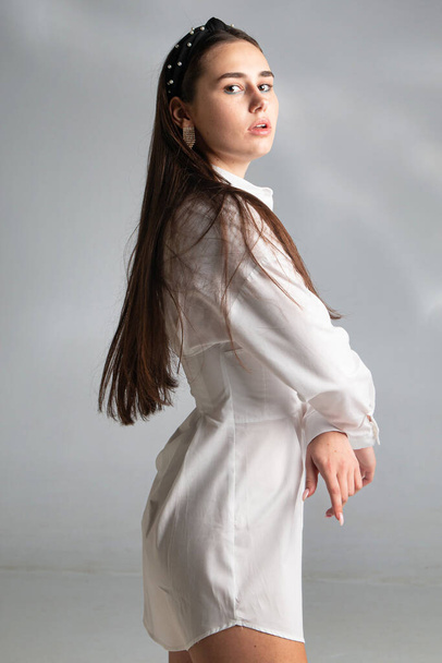 Young woman with dark hair in white long sleeve blouse isolated on grey - Foto, immagini