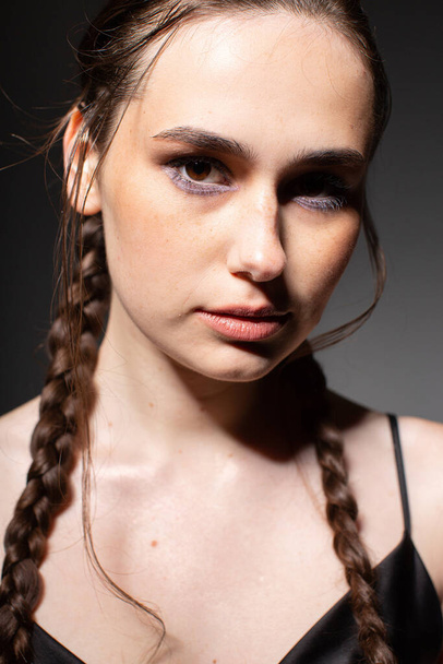 Portrait of dark hair young european woman with two braids with brown eyes isolated on dark grey - Photo, Image