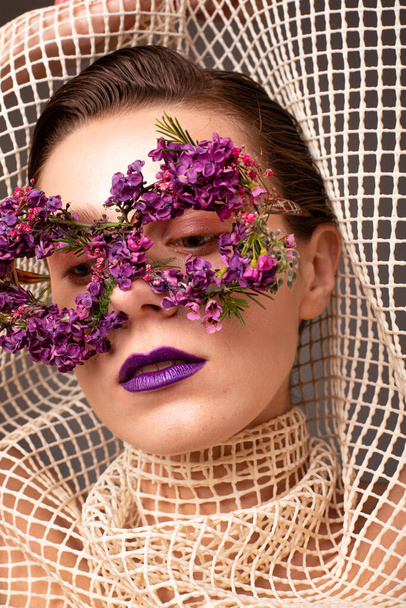 Young woman with eye mask made of small flowers with purple lips portrait - Фото, зображення