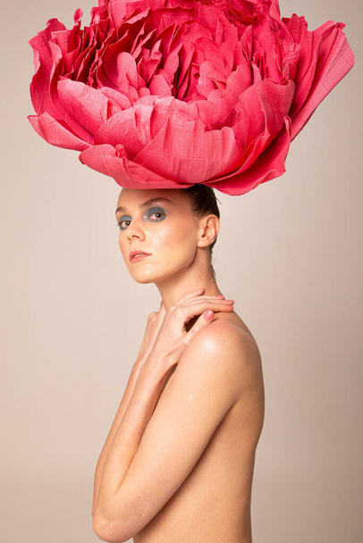 Naked young woman wearing pink peony hat isolated on dark beige - Foto, immagini