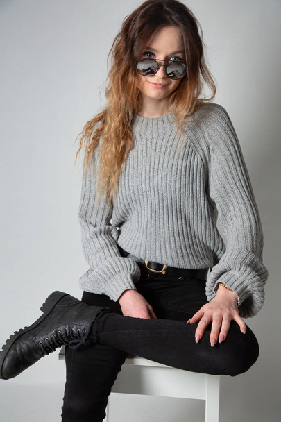 White young european woman with long curly hair in grey knitted jumper isolated on grey in sun glasses - Foto, Bild