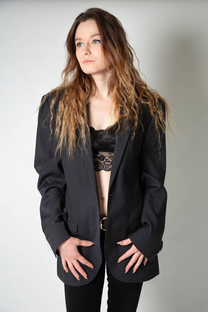 White young european woman with long curly hair isolated on grey in black jacket - Foto, Imagem