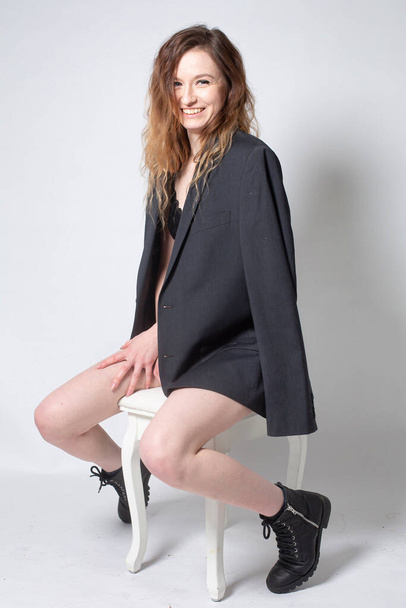 White young european woman sitting on the chair isolated on light grey in total black - Foto, immagini