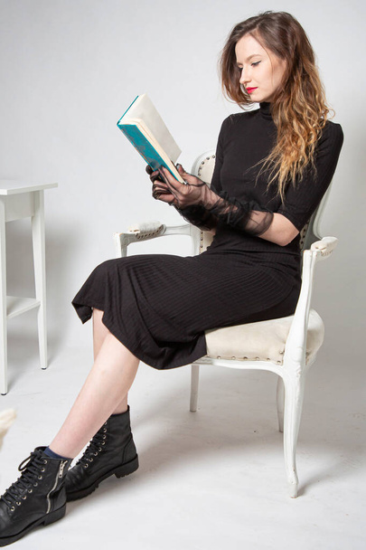 White young european woman sitting in chair with a book in total black - Photo, image
