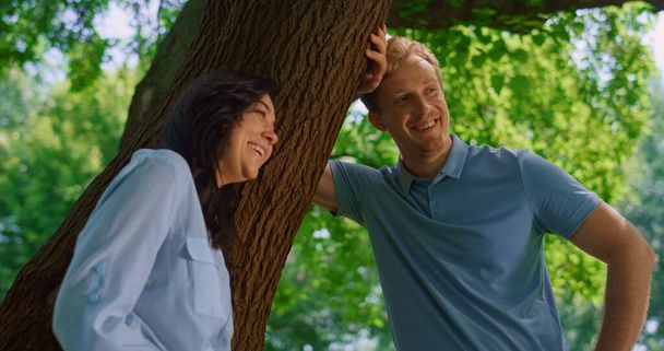 Lovely couple talking lean on tree close up. Pretty wife laughing with husband. - Photo, Image