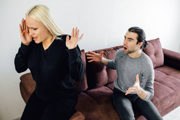 Aggressive caucasian Husband Shouting At Unhappy Victimized Wife Sitting On Couch At Home. - Valokuva, kuva