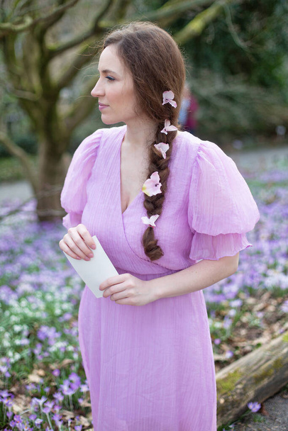 European woman in lilac dress with flowers in hair in park - Zdjęcie, obraz
