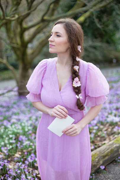 European woman in lilac dress with pigtail in park - Photo, Image