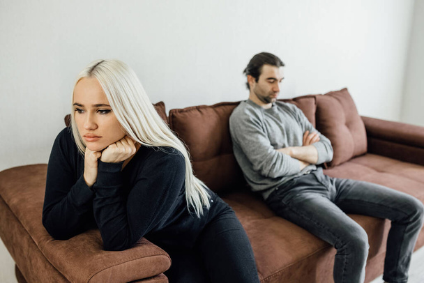 Focus on stressed angry young woman sitting separate on couch with stressed offended husband. - Foto, imagen