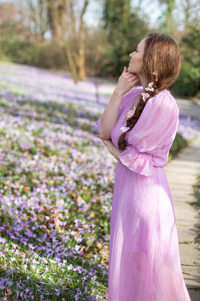 European woman in lilac dress with flowers in hair in park on a spring day - Foto, Imagem