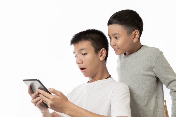 asijské teenager a jeho bratr vidění překvapení na jeho tablet - Fotografie, Obrázek