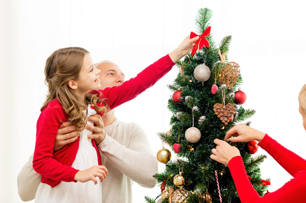 smiling family decorating christmas tree at home - Foto, imagen