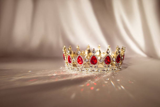 Χρυσό στέμμα με κόκκινους πολύτιμους λίθους, αξεσουάρ για βασιλιάδες και βασίλισσες, πρίγκιπα και πριγκίπισσα. Παραμύθι. Σύμβολο εξουσίας και πλούτου. - Φωτογραφία, εικόνα