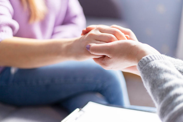 Großaufnahme einer Psychologin, die während einer Therapiesitzung die Hände der Frau hält. Psychotherapeutin unterstützt depressive Patientin. - Foto, Bild
