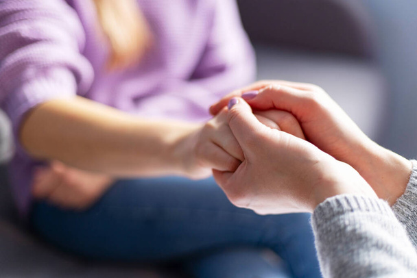 Terapi seansı sırasında bir kadının elini tutan kadın psikoloğun yakın çekimi. Depresyondaki hastasını destekleyen psikoterapist. - Fotoğraf, Görsel