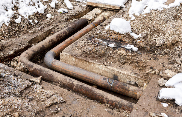 Replacement of heating pipes and modernization of the heating system. Repair of old rusty metal pipes. Construction works on iron pipes at a depth of excavated trench - Photo, Image