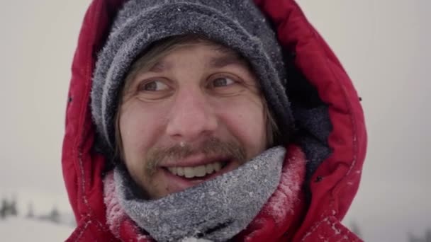 冬のジャケットを着た男と雪の間に雪を歩く帽子、雪を吹いて、サイクロン中の強風、雪の嵐から顔を隠す. - 映像、動画