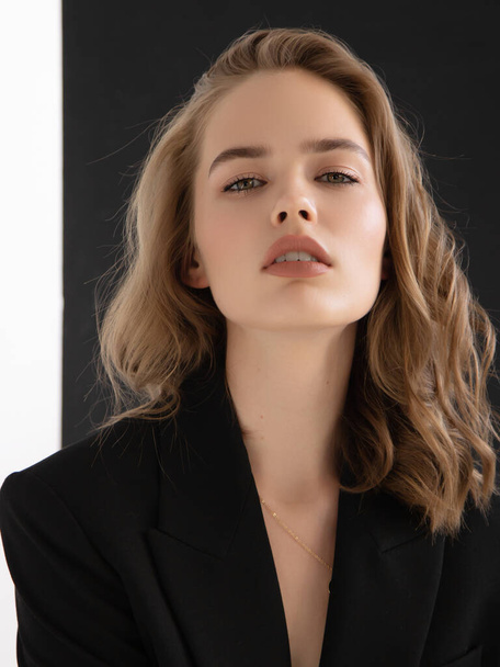 Natural look. Beauty model woman . Model test portrait with young beautiful fashion model posing on grey background. Blond woman in a black blazer . Natural makeup - Photo, Image