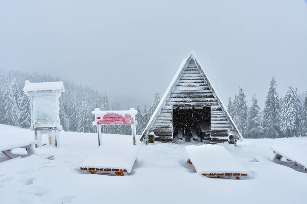 Paisaje invernal en las montañas polacas de los Sudetes, refugio turístico cubierto de nieve en una ruta de senderismo de montaña, cubierta de nieve gruesa, día nublado y nublado. - Foto, Imagen