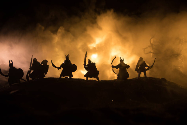 騎兵や歩兵との中世の戦闘シーン。中世の城と暗いトーン霧の背景に戦士の間で戦う、別のオブジェクトとしての人物のシルエット。選択的焦点 - 写真・画像
