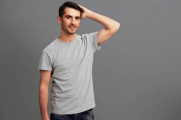 portret man casual slijtage grijs t-shirt plezier hand gebaar grijs achtergrond - Foto, afbeelding