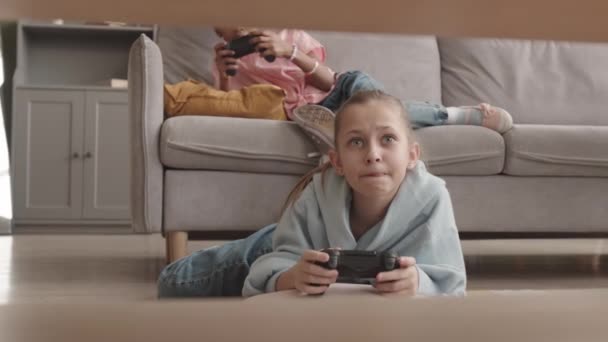 ゆっくりの白人女の子とともにジョイスティック遊びビデオゲーム横たわっ上の階に自宅で余暇時間 - 映像、動画