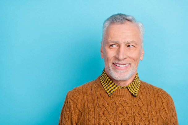Photo of attractive dreamy retired man wear brown sweater looking empty space isolated blue color background - 写真・画像
