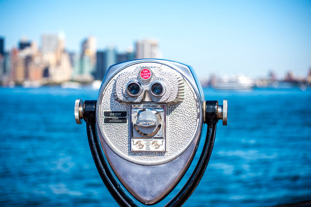 НЬЮ-ЙОРК, США - СЕНТЯБРЬ, 2019 г.: Вид на винтажный бинокль на острове Свободы, вид на Манхэттен на заднем плане - Фото, изображение