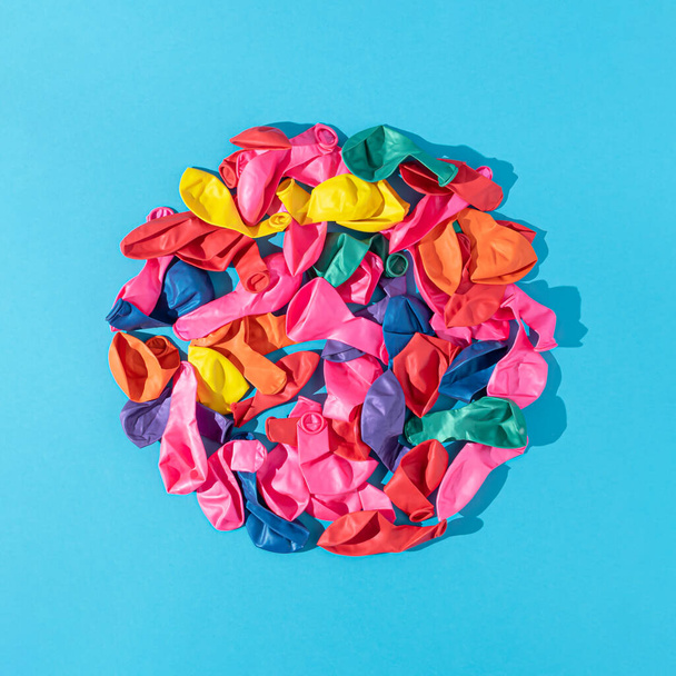 Colorful balloons arranged in circle on bold blue background. Minimal party concept. Flat lay with sunny day shadows. - 写真・画像