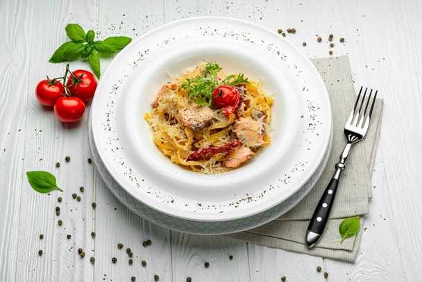 Éttermi étkezés. Olasz tészta lazaccal, sajttal és paradicsommal - Fotó, kép