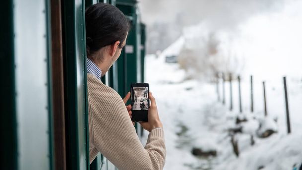 Pohled na jedoucí parní vlak Mocanita zevnitř, v zimě holý les, filmování cestujících, sníh, Rumunsko - Fotografie, Obrázek