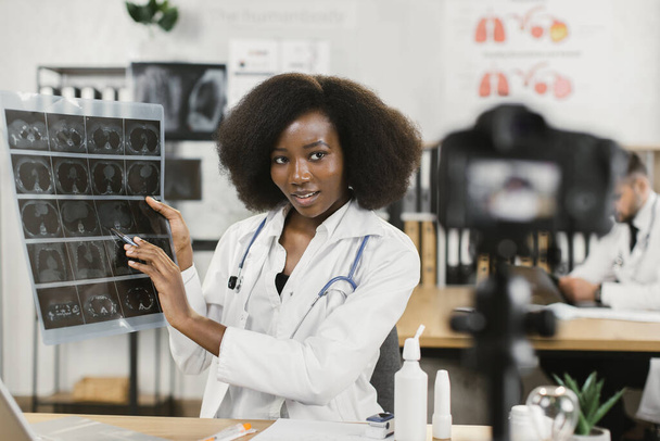 African female doctor showing x ray scan while filming vlog - Foto, immagini