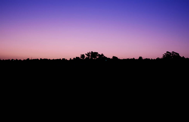 paesaggio in silhouette di montagne al tramonto che dipinge il cielo in colori viola e rosa in contrasto con il nero delle montagne - Foto, immagini