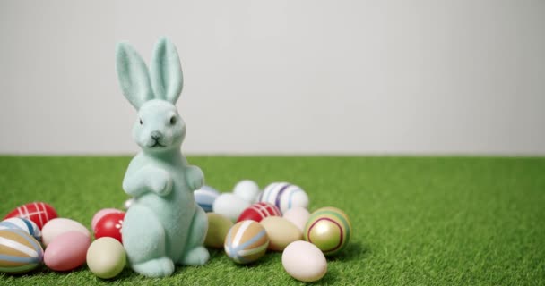 Rabbit Toy on a White background of green grass with many colored eggs, Text. - Footage, Video