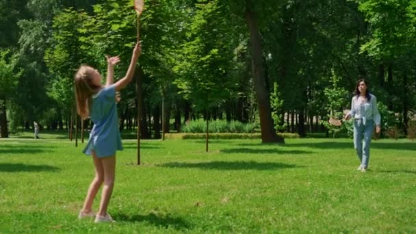 Vidám lány tollaslabdázik anyával a parkban. Aktív családi pihenőidő fogalma. - Felvétel, videó