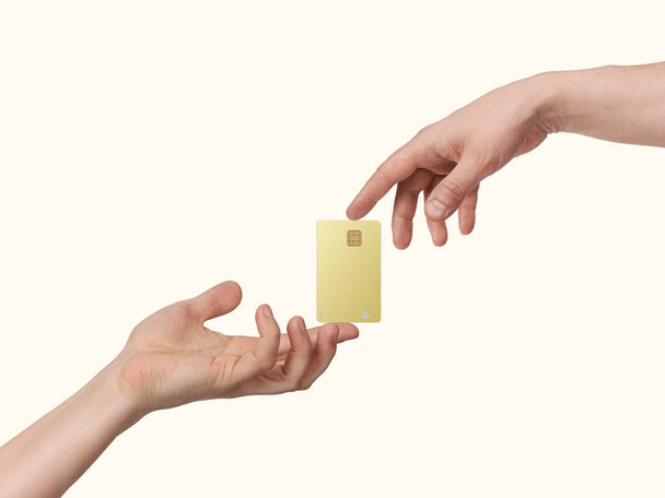 Las manos mantienen la tarjeta bancaria de oro en el centro de atención, aislada en fondo beige claro - Foto, Imagen