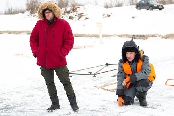Montéři v zimním oblečení si povídají na ledě zamrzlého jezera - Fotografie, Obrázek