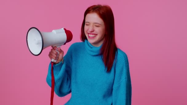 Uśmiechnięta ruda dziewczyna rozmawiająca z megafonem, głosząca nowiny, głośno ogłaszająca reklamę sprzedaży - Materiał filmowy, wideo