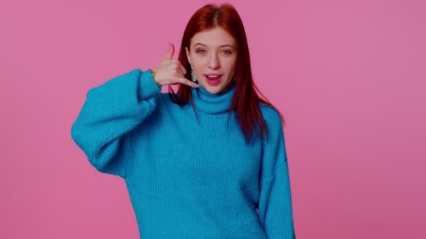 Fröhliches Mädchen im blauen Pullover, das in die Kamera schaut und Handygesten macht, als würde es sagen: "Hallo, du rufst mich zurück" - Filmmaterial, Video