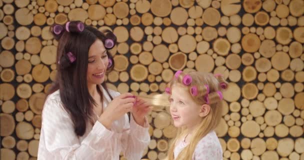 Γυναίκα κουλουριάζει τα μαλλιά της κόρης της στο σπίτι - Πλάνα, βίντεο