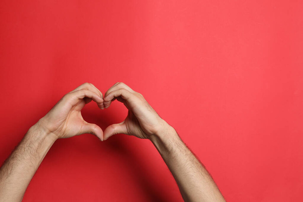 Man making heart with his hands on red background, closeup. Space for text - Foto, immagini
