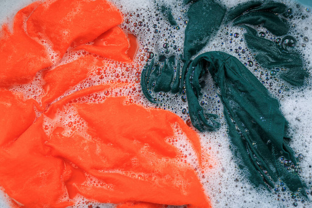 Colorful clothes in suds, top view. Hand washing laundry - Foto, immagini