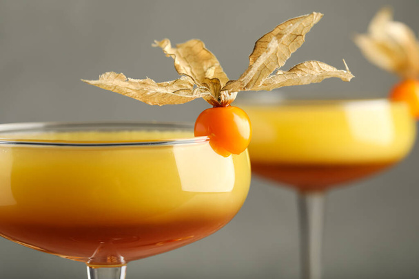 Tasty cocktail decorated with physalis fruits on grey background, closeup - Foto, afbeelding