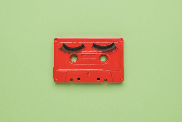 Una grabadora de cinta roja con pestañas grandes sobre un fondo verde claro. Imagen creativa. El concepto de grabación de sonido analógico. Puesta plana. - Foto, imagen
