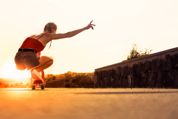 Beautiful young girl on his longboard on the road in the city in sunset day. Extreme sports, rear view of motion. Copy space. Lifestyle and sport concept. - Fotoğraf, Görsel