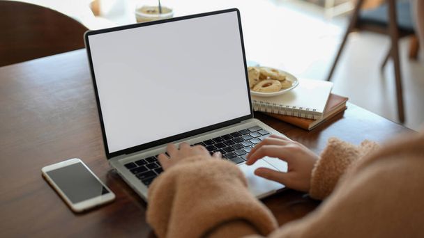 携帯型ラップトップコンピュータに入力する女性、居心地の良いカフェでリモートワーク、彼女のオンライン課題を行い、ソーシャルメディアに時間を費やしています。ノートパソコンの白い画面のモックアップ - 写真・画像