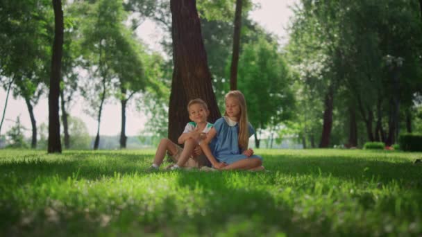 Vreugdevolle kinderen die onder de boom spelen. Lachende kinderen hebben plezier buiten in het weekend. - Video