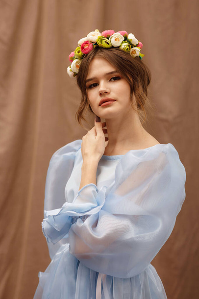 portrait of a girl in a blue dress with a wreath of flowers - Zdjęcie, obraz
