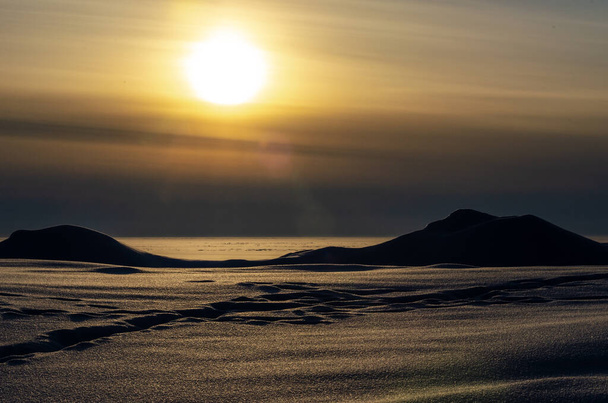 A desert snowy landscape in the rays of the setting sun. Snowdrifts at sunset. - Fotó, kép