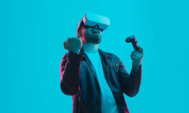 Player in VR glasses celebrating win in videogame - Photo, Image